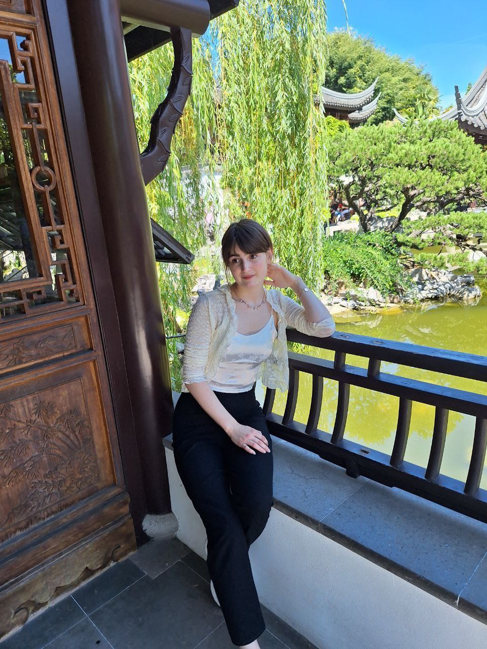 Jessica Thompson sitting on a traditional wooden balcony with a scenic garden view.