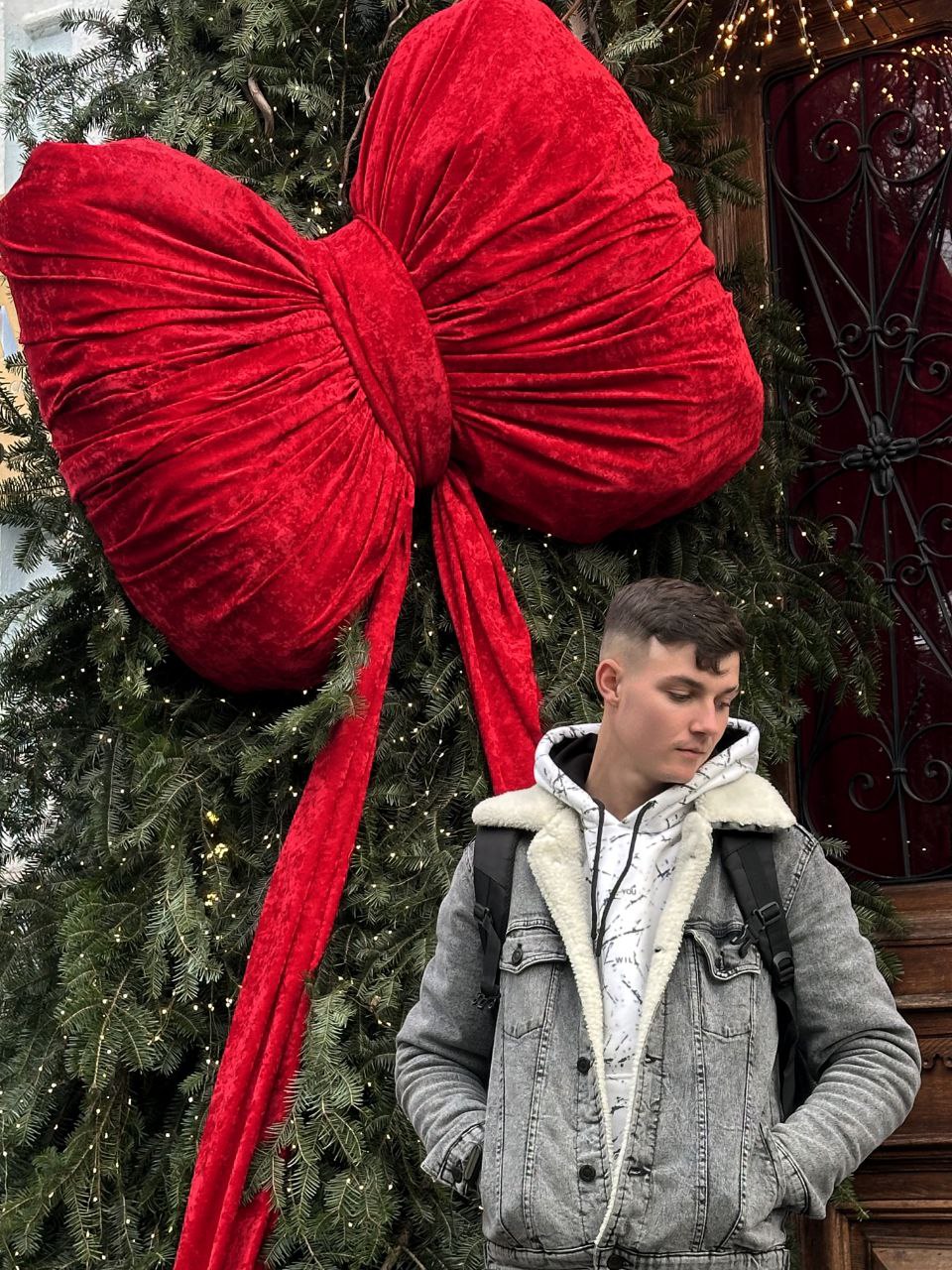 Michael Harris standing next to a large red bow on a Christmas tree