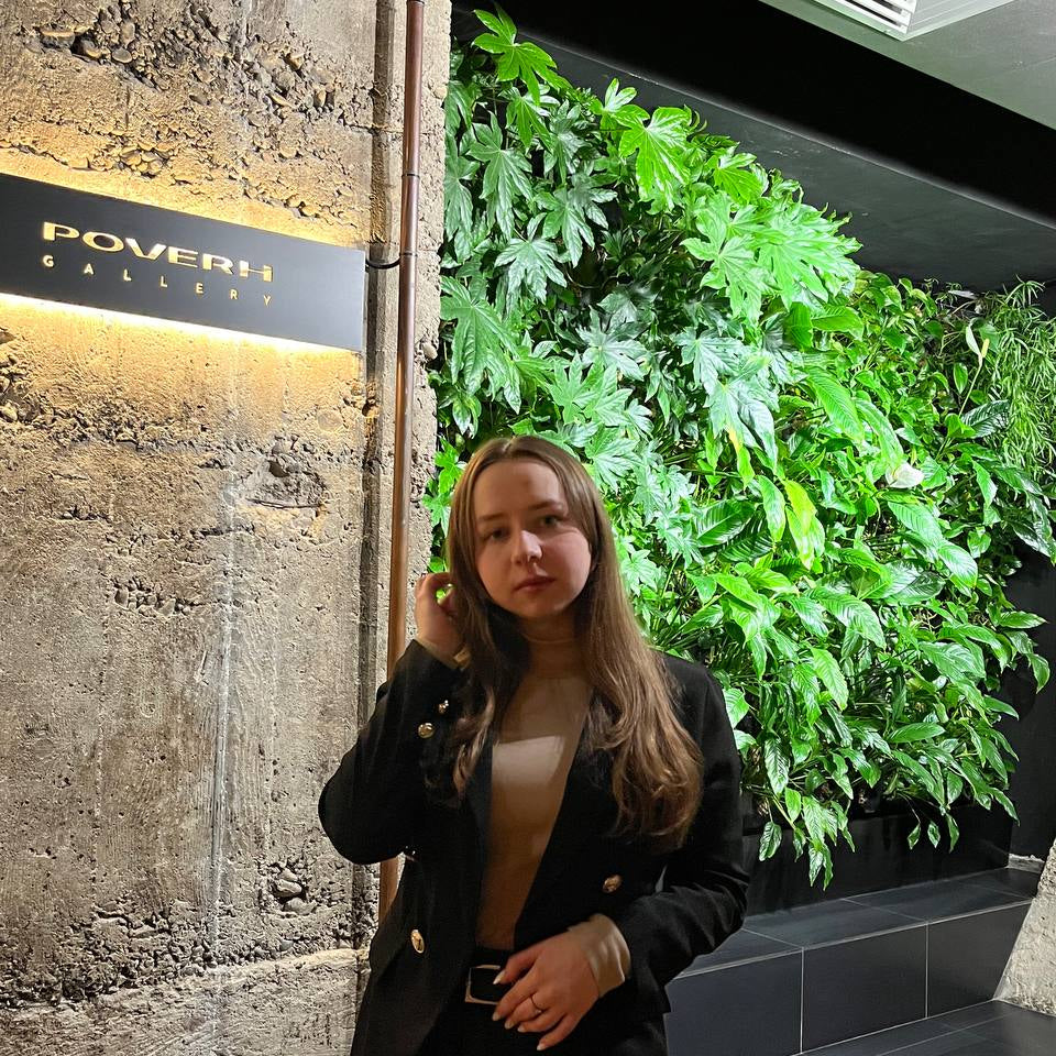 Kasia Jablonska in a black suit standing next to a green wall